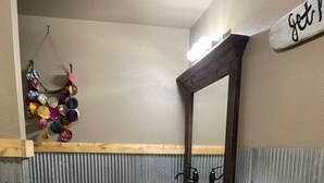 Un baño pequeño con tocador de madera, lavamanos verde, espejo y perchero.
