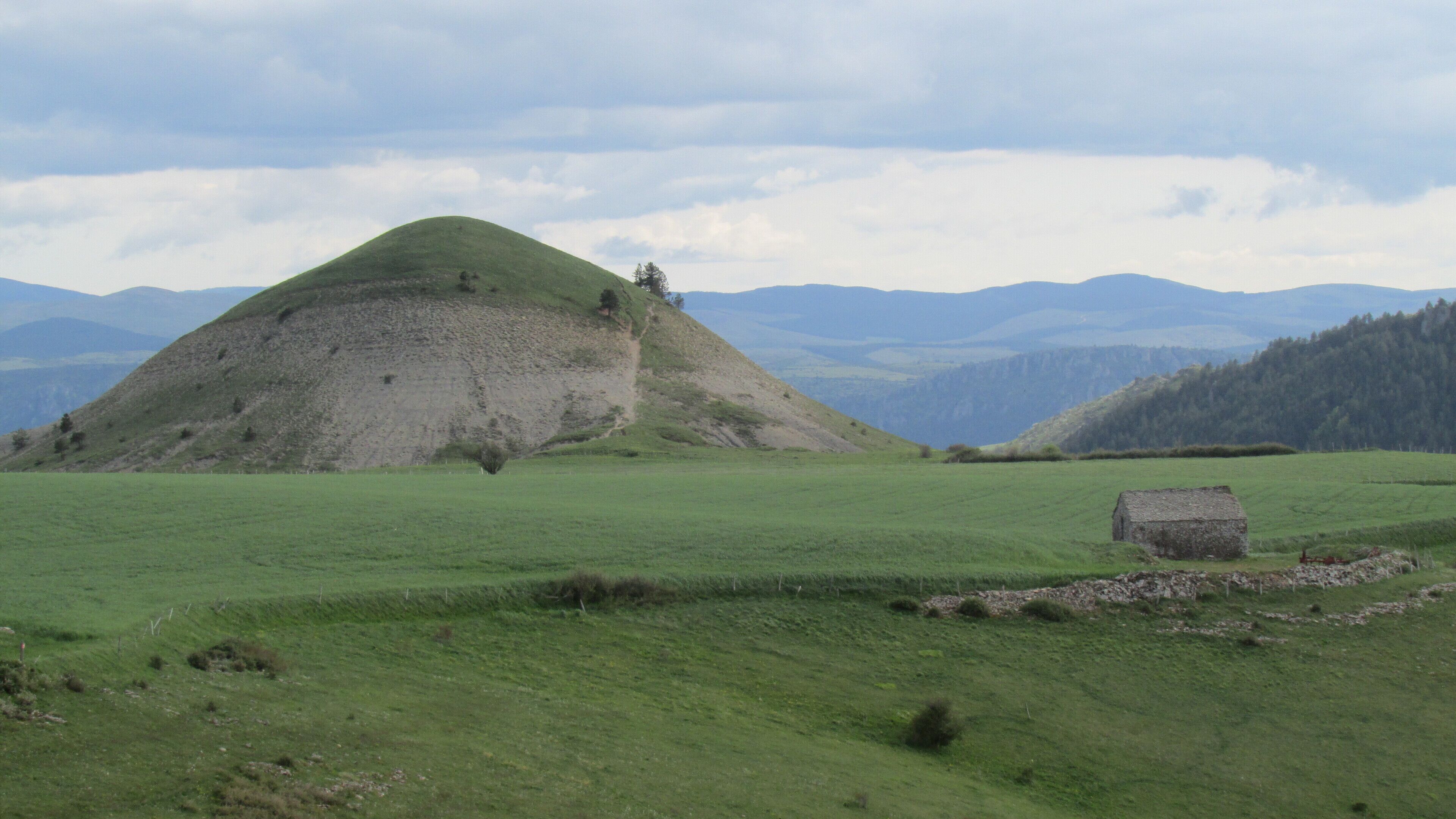 A grassy field with a mound and a stone structure.