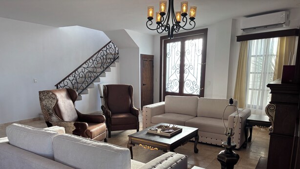 A living room with a staircase, leather armchairs, a sofa, and a coffee table.