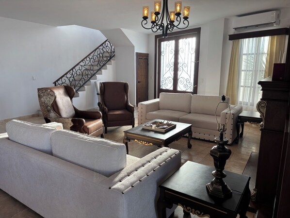 A living room with a staircase, leather armchairs, a sofa, and a coffee table.