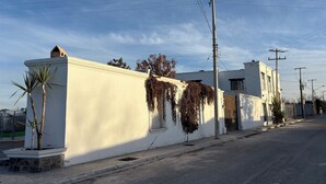 A white building with a flat roof, a small window, and a door. There are power lines and a utility pole visible.