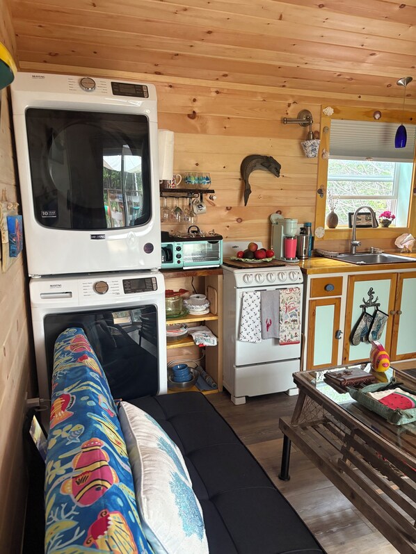 Eine kompakte Küche mit Herd, Backofen, Mikrowelle und Toaster. Ein Holzboden und ein Fenster mit Blick.