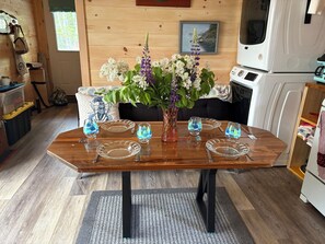 Een eettafel met glazen servies en borden, een vaas met bloemen, en een houten vloer.