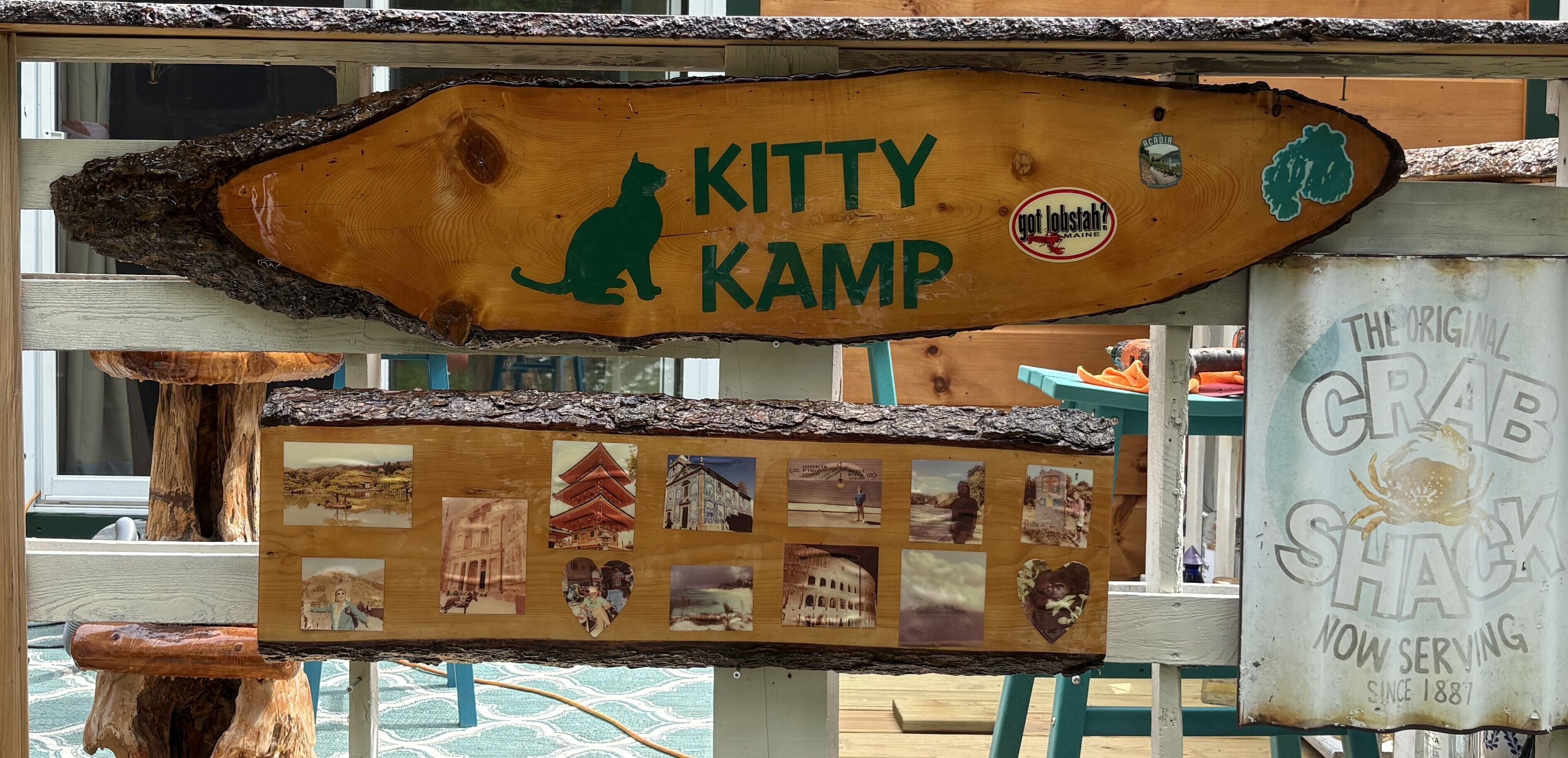 A wooden sign with a cat silhouette and the text "KITTY KAMP" and "got lobster?" stickers.