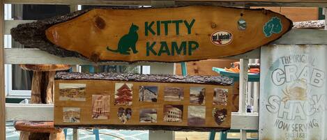A wooden sign with a cat silhouette and the text "KITTY KAMP" and "got lobster?" stickers.