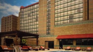 Un hotel con piscina, zona de estar al aire libre y un edificio grande de ladrillo con ventanas amplias.
