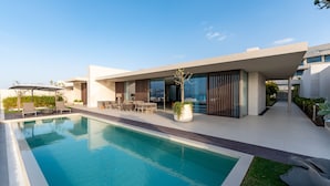 Ein modernes Haus mit Swimmingpool, Gartenmöbeln und einem gepflegten Garten.