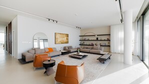 Ein modernes Wohnzimmer mit einer Sofagarnitur, einem Couchtisch und einem orangefarbenen Sessel.