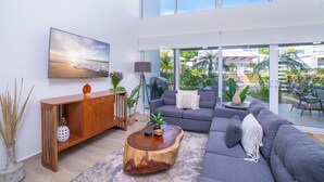 A modern living room with a gray sectional sofa, a wooden coffee table, and a large TV mounted on the wall. - Luxury Walk-to-Beach 3BR Oasis , Playa Avellanas (Playa Avellanas)