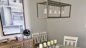 Un comedor con una mesa larga, seis sillas, un banco y una araña.