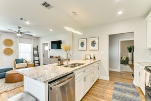 A modern kitchen with a granite countertop, stainless steel appliances, and white cabinetry. - Walk to the Strand! Sleeps 14! (Galveston)