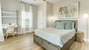 Un dormitorio con cama, escritorio, silla, ventilador de techo e iluminación empotrada en la pared.