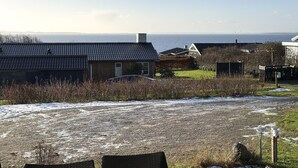Una zona residenziale costiera con case, un vialetto sterrato e vista sul mare.