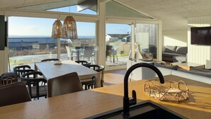 Una cucina moderna con una grande finestra, un'area pranzo e un soggiorno con divano e televisore.