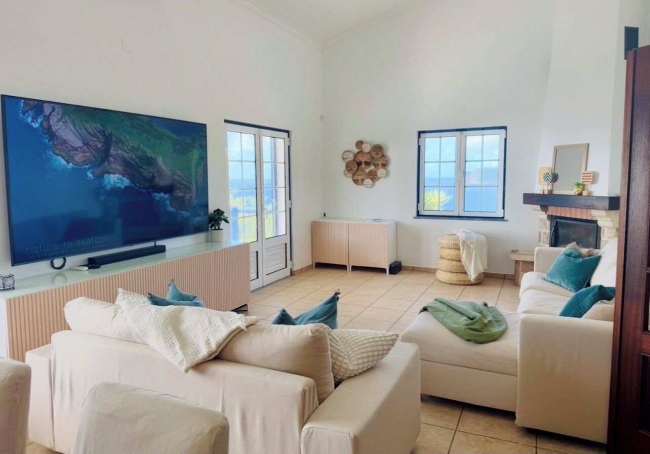 A spacious living room with two sofas, a flat-screen TV, and a fireplace.