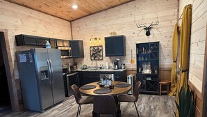 Una cocina acogedora con paredes de madera, una mesa redonda y un refrigerador.