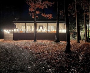 A cabin with a deck, surrounded by trees and a leaf-covered ground. - Ruby’s Retreat in Mountain Resort (Ellijay)