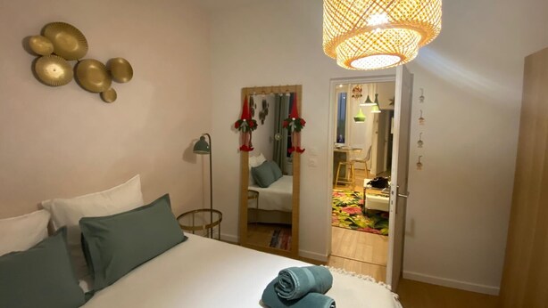 Une chambre à coucher avec un lit, des oreillers, une lampe de chevet, un miroir et un luminaire suspendu.