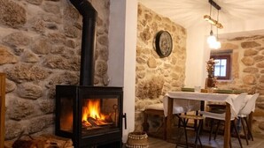 Um quarto acolhedor com parede de pedra, lareira, mesa de jantar com cadeiras e tapete estampado.