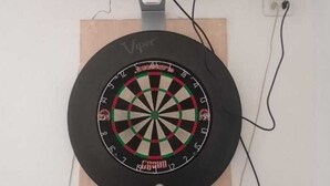 Un dardo colgado en una pared, con un televisor encima.