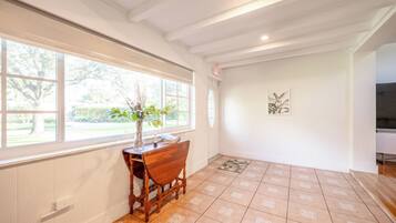 A room with a large window, wooden furniture, and a tiled floor.