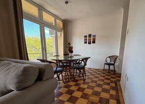 A living room with a checkered floor, a round glass table, and a sofa. - Apto Pet Friendly com Ar condicionado no Centro (Bagé)