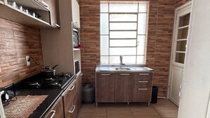 A kitchen with a gas stove, a sink, and wooden cabinets.