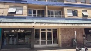 A two-story building with a ground-level shop named 'DetailHE' and a balcony on the upper floor.