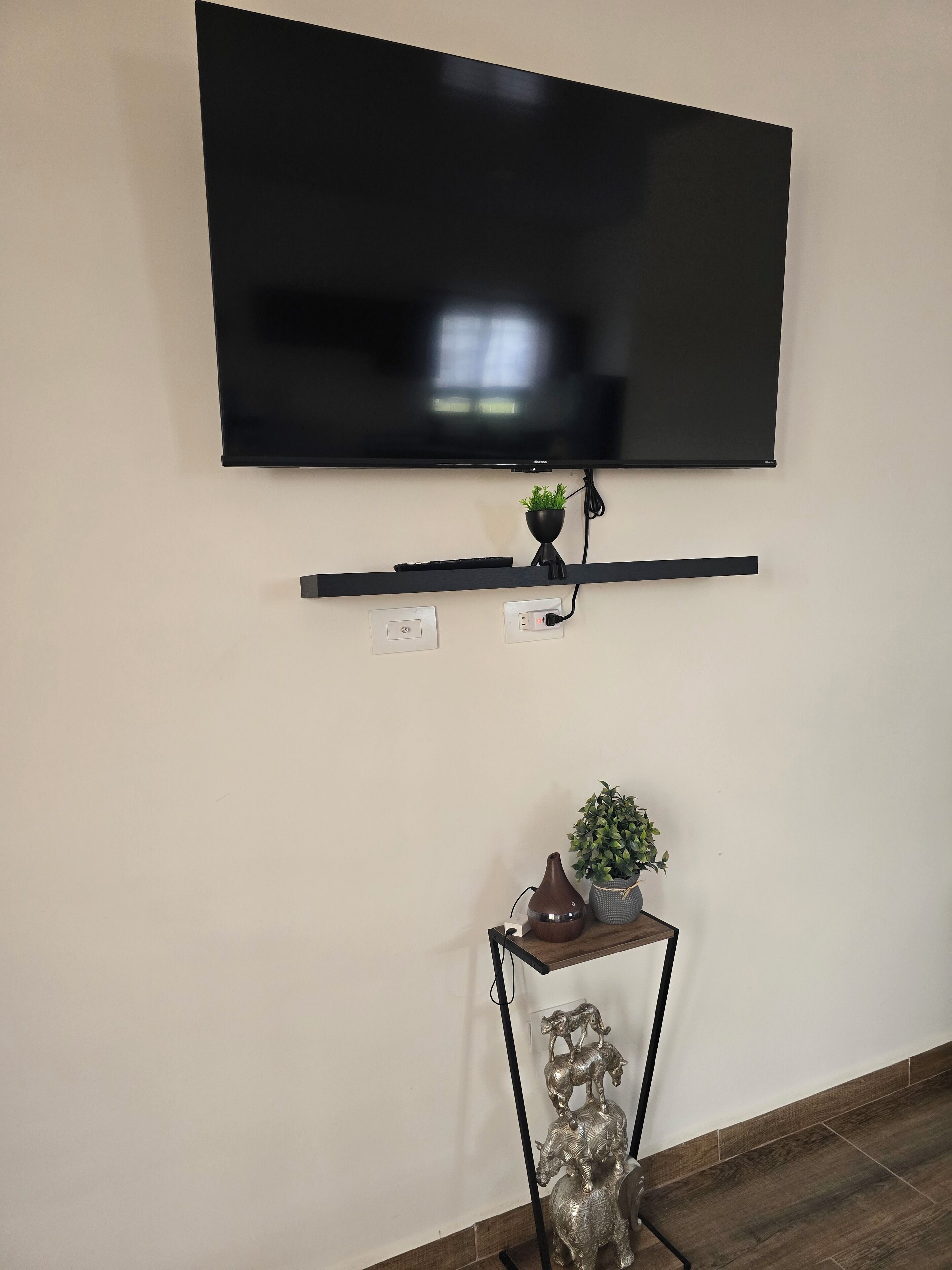 Een flatscreen-televisie bevestigd aan een wand, met een plank eronder.