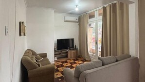 Un salon avec un canapé, un téléviseur et un revêtement de sol à motifs.