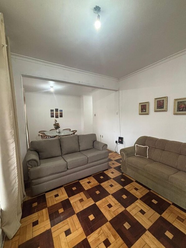 A living room with two sofas, a patterned wooden floor, and a dining area in the background.