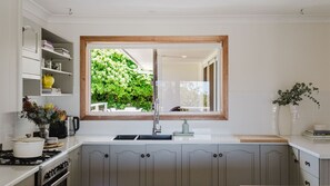 A kitchen with a window, cabinets, a sink, and a stove. - Light House in Mollymook Beach (Mollymook Beach)