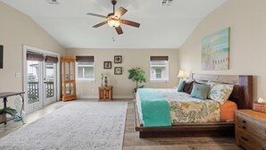 A spacious bedroom with a large bed, a ceiling fan, and a balcony door. - GetawaY at Mi Casita (Rockport)