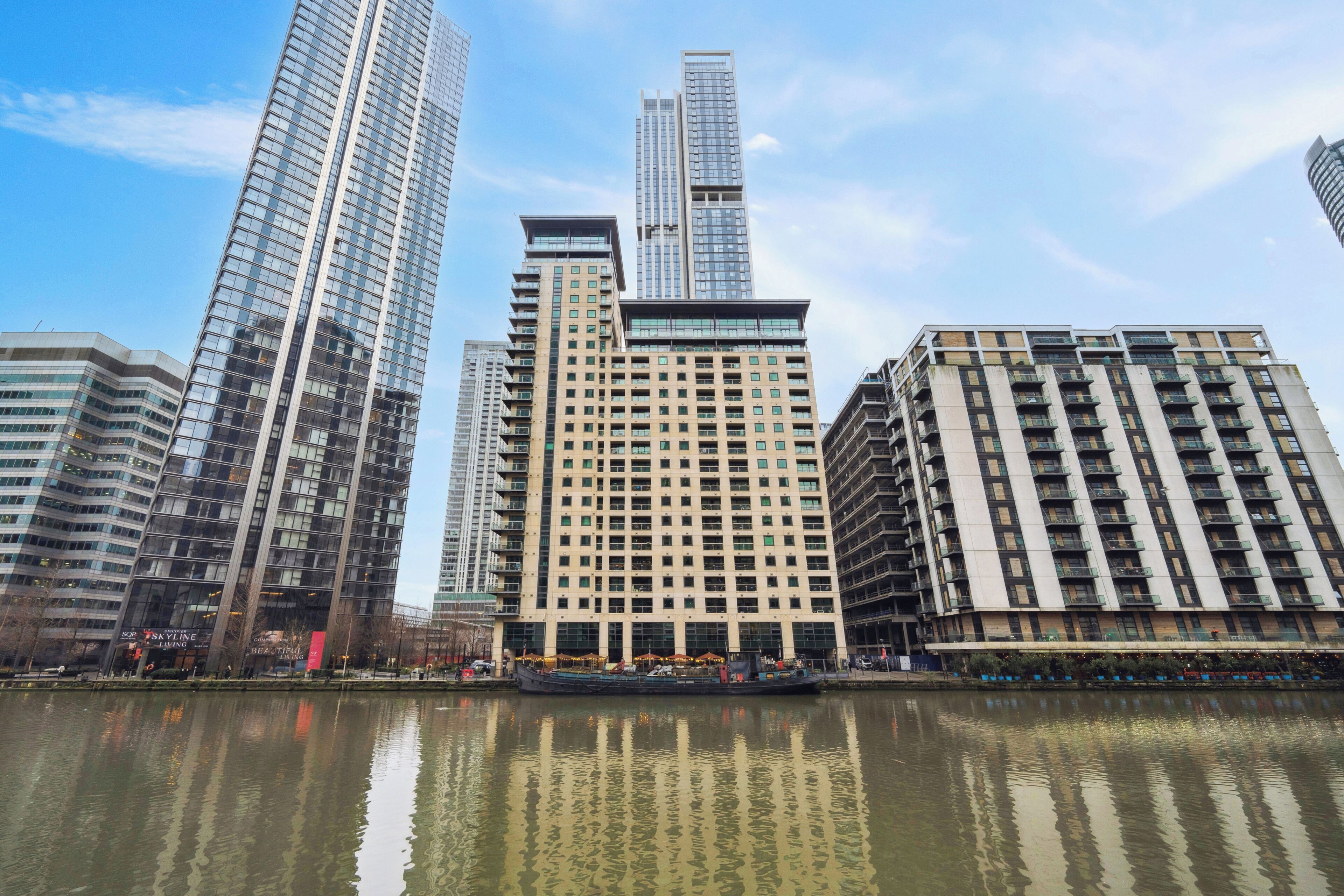 A high-rise hotel with multiple floors, a central courtyard, and a reflection in the water.