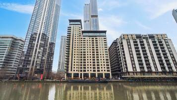 A high-rise hotel with multiple floors, a central courtyard, and a reflection in the water.