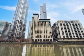 A high-rise hotel with multiple floors, a central courtyard, and a reflection in the water. - River View 2 bed 2 bath Penthouse Canary Wharf (London)