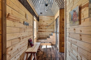 A wooden interior with a bench, a staircase, and a painting on the wall. - Rustic Barn Retreat w Hot Tub, Game Room & FirePit (Wardensville)