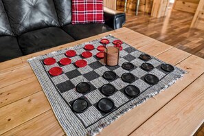 A checkered board game with red and black pieces on a wooden table. - Rustic Barn Retreat w Hot Tub, Game Room & FirePit (Wardensville)