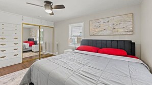Ein Schlafzimmer mit einem Bett, einem Kleiderschrank, einem Deckenventilator und einem Fenster mit Jalousien.