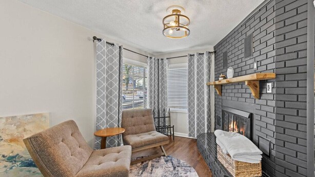 Ein gemütliches Wohnzimmer mit Kamin, zwei Sesseln, einem kleinen Tisch und einem Teppich.