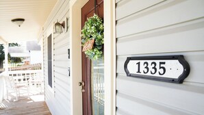 A house number 1335 on a white house with a wooden porch and a door. - The Southern Porch Cottage Near NOLA & Coast (Slidell)