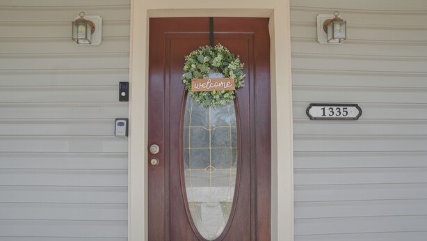 A wooden front door with a welcome sign, a glass door with a grid pattern, and a house number sign. - The Southern Porch Cottage Near NOLA & Coast (Slidell)
