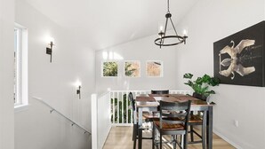 A dining area with a wooden table and chairs, a chandelier, and a painting of swans on the wall. - Charming 3-bedroom house in Homer perfect for your getaway (Homer)