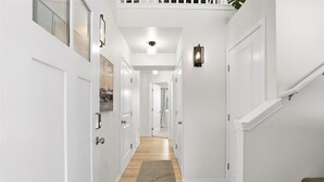 A hallway with white walls, wooden flooring, and a staircase on the right. - Charming 3-bedroom house in Homer perfect for your getaway (Homer)