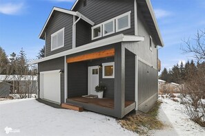 A two-story house with a garage, a front porch, and a wooden deck.