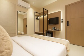 A hotel room with a bed, a TV, a mirror, a wardrobe, and a small kitchenette. - M Square Express (Indore)