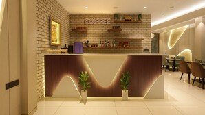 A modern coffee bar with a brick wall backdrop, shelves with coffee equipment, and a seating area with chairs and a table. - M Square Express (Indore)