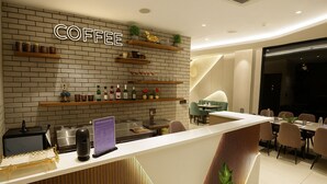 A modern coffee shop with a brick wall, shelves with coffee equipment, a counter with a menu, and seating areas. - M Square Express (Indore)