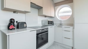 A modern kitchen with white cabinets, a built-in oven, a microwave, and a toaster. - Dean Swift Square (Dublin)