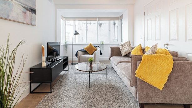 A modern living room with a sofa, coffee table, and TV stand. - Dean Swift Square (Dublin)